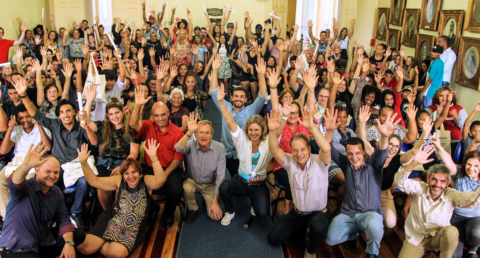 A group of people poses for a photo with happy faces and hands in the air celebrating 4 years of PPP - Pacto Pelotas Pela Paz -