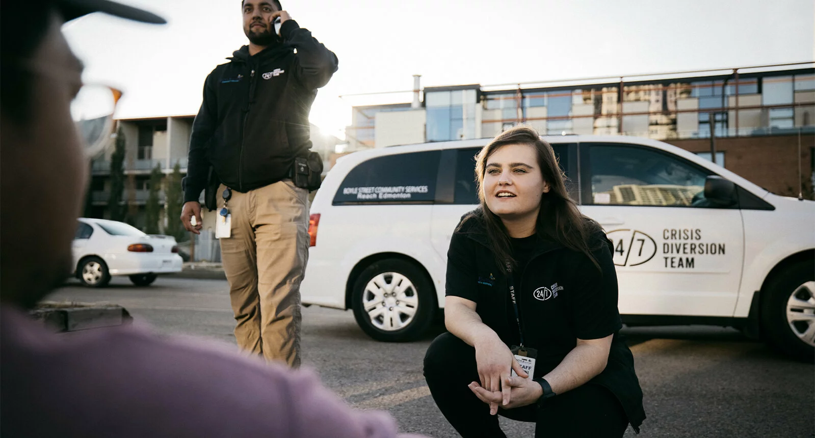 A man and a woman talking to a man in front of a 24/7 Crisis Diversion Team white van