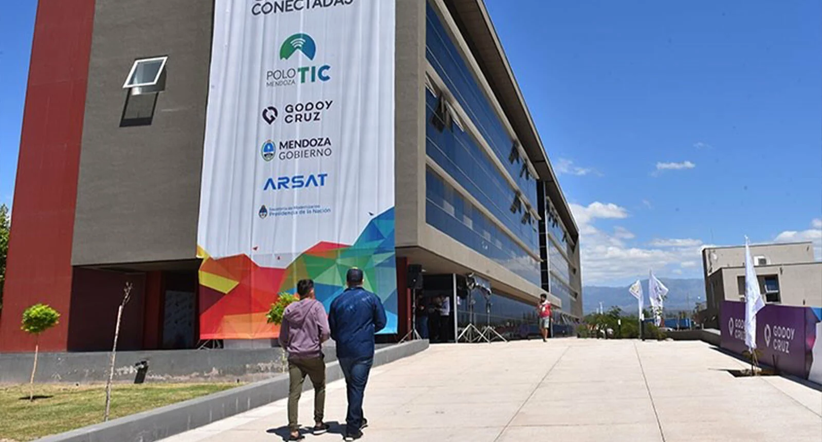 Two individuals are walking towards the Mendoza TIC Parque Tecnológico