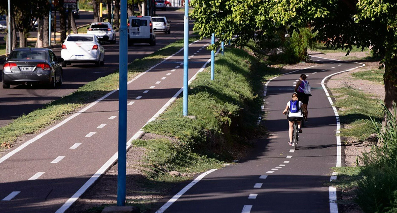 Two people bike on beautiful and spacious cycle paths next to car traffic in Godoy Cruz