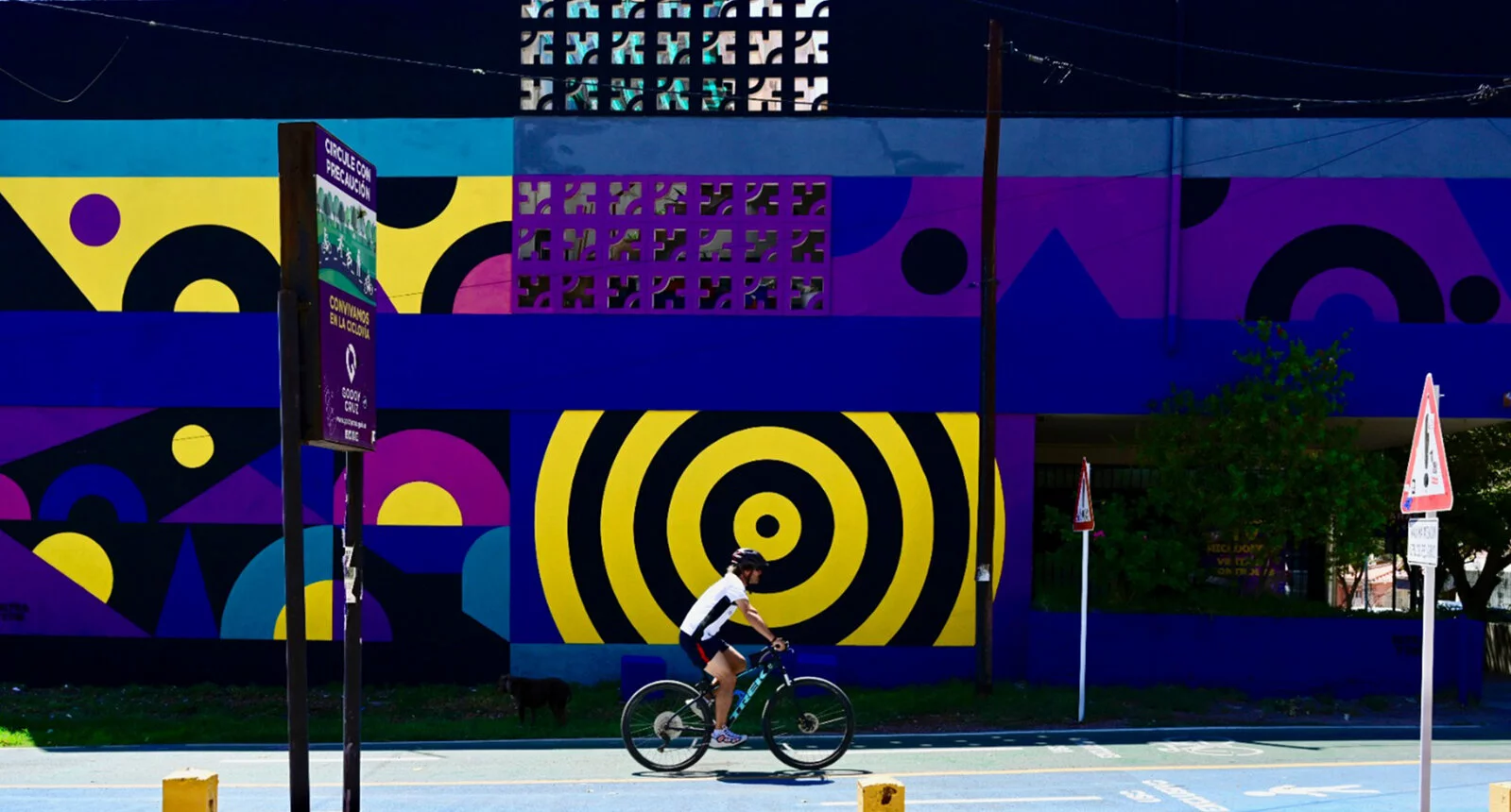 A man rides a bike with colorful murals next to him