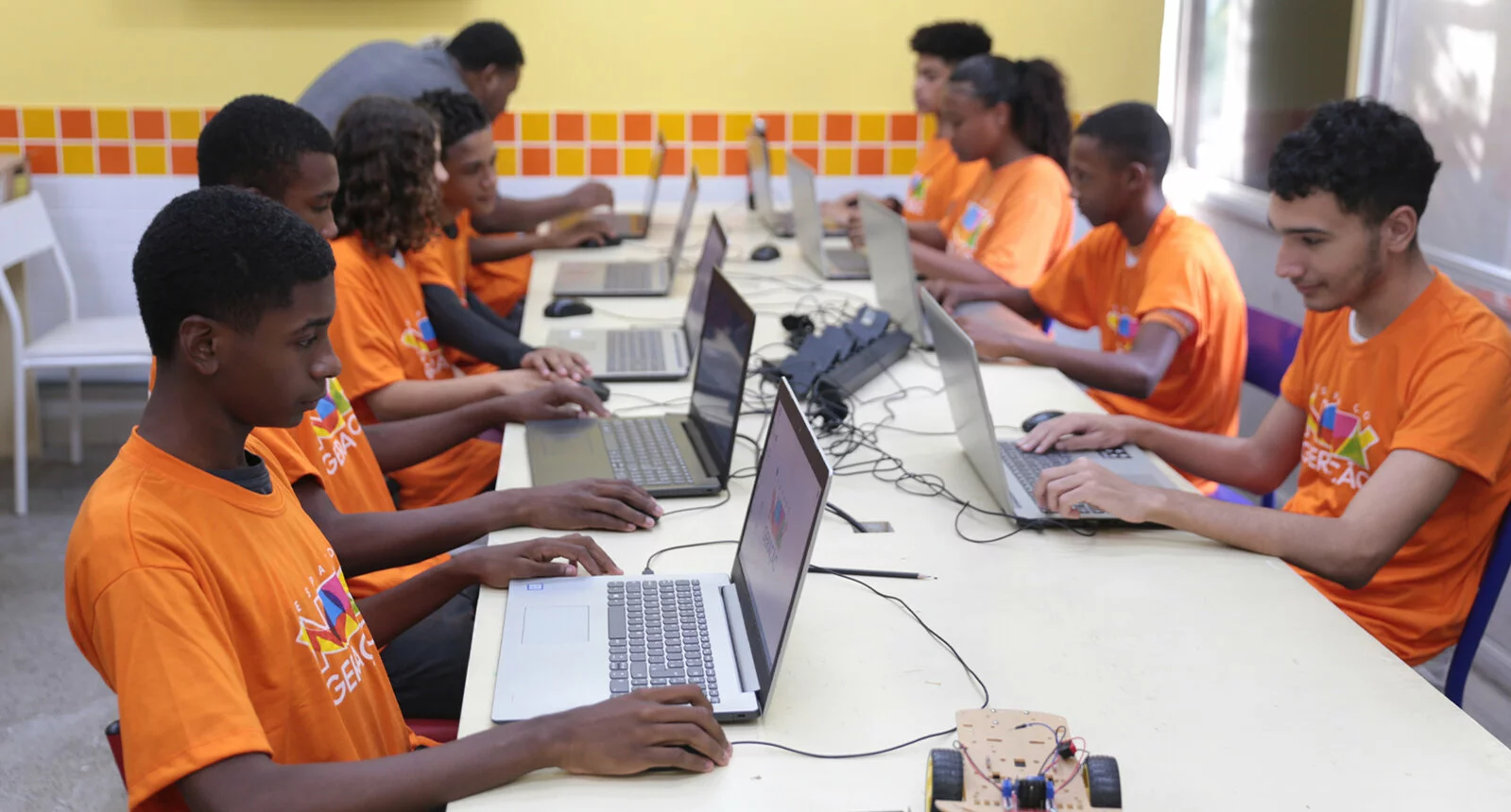 Several students sit at laptop computers at a table in the new generation space