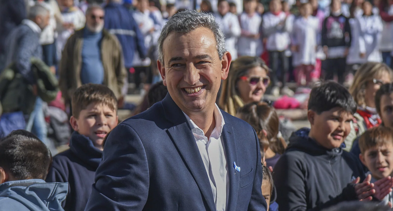 Pablo Javkin, Mayor of Rosario, Argentina, smiles in the foreground while children stand behind him smiling and clapping.