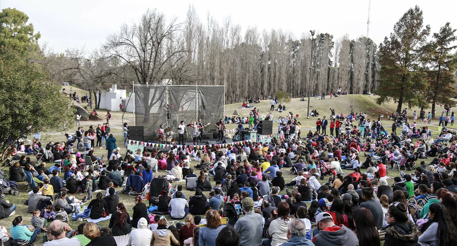 A crowd of people sits enjoying children's shows at La Granja de la Infancia